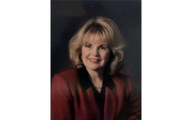 A portrait of a woman with blonde hair wearing a red suit.