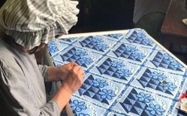 A woman working on a blue quilt