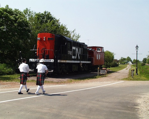 Image of the Kensington Locomotive and two bagpipers in front of it.